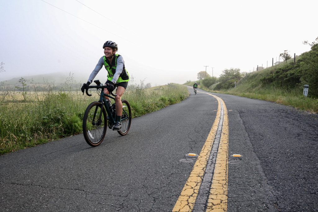 A person on a bicycle rides on a road in the fog
