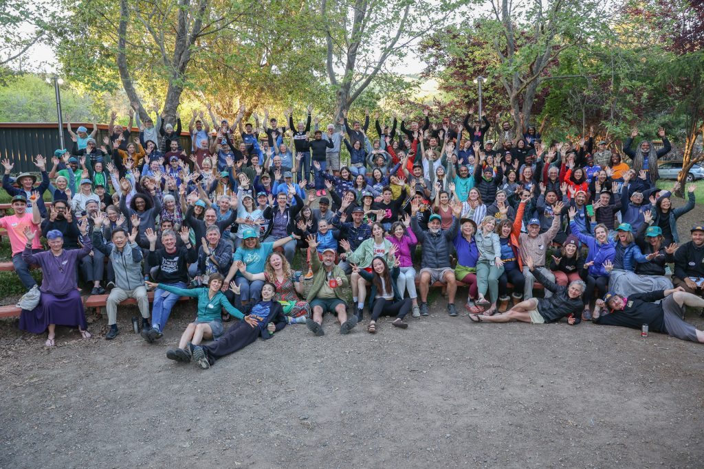 A large group of people poses with their hands up